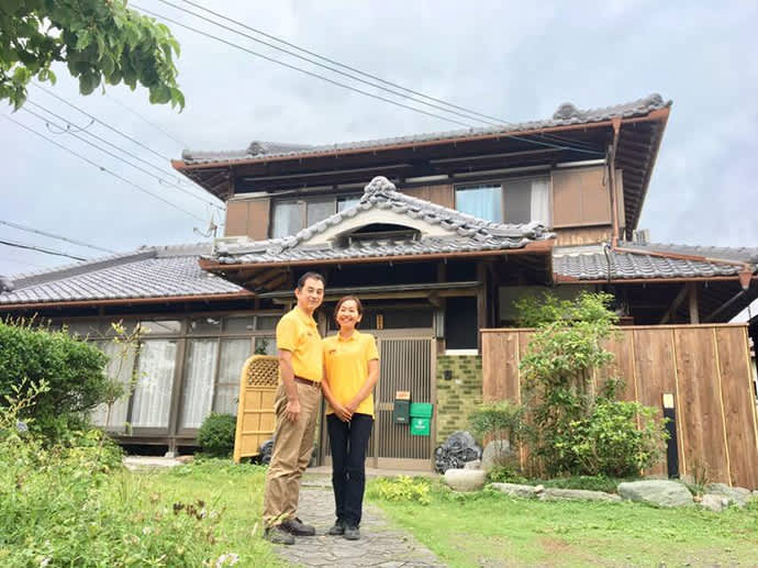 Mr. and Mrs. Toyoda stand in front of their farmhouse, Farmhouse NaNa.