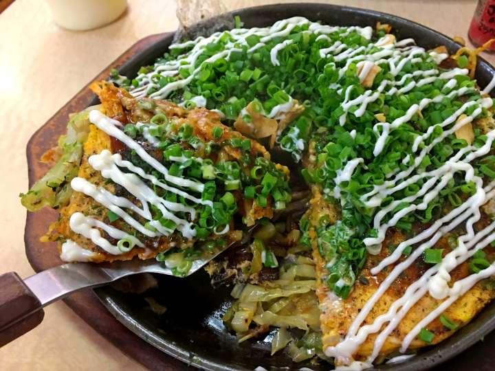 a savory pancake topped with meat and vegetables of okonomiyaki in Hiroshima