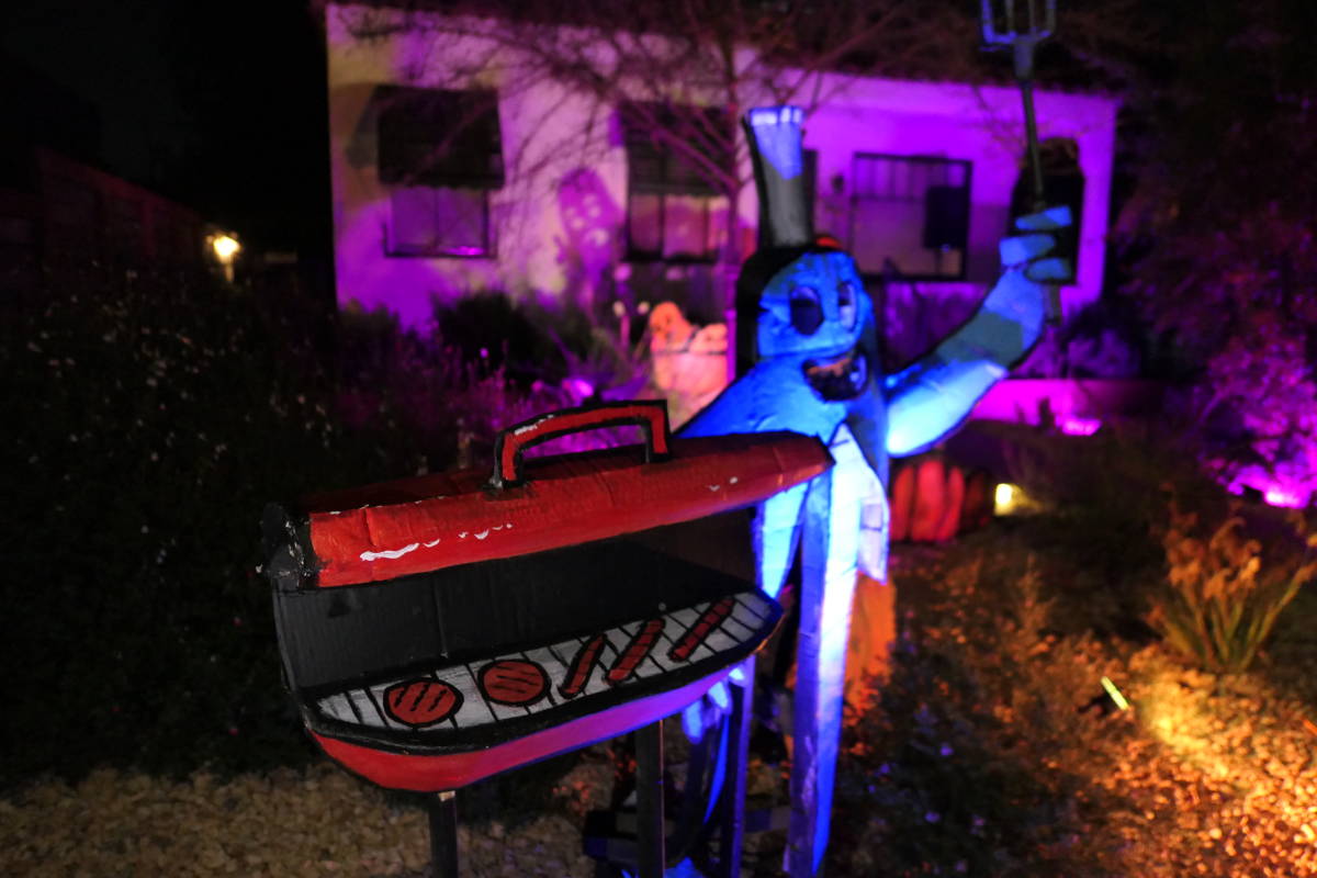 A leggy ghost cooking up hot dogs and hamburgers on a classic red grill