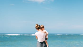 a person holding a baby on a beach