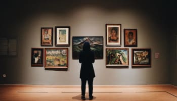 a person standing in front of a wall with paintings