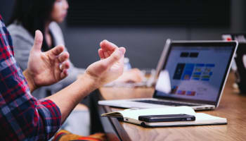 a person clapping hands in front of a laptop