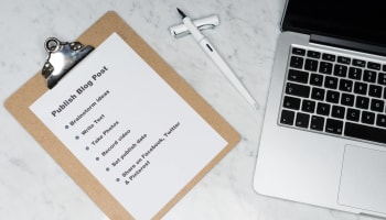 a clipboard with a notepad and a pen on a marble surface