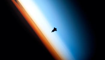 a silhouette of a space shuttle in space