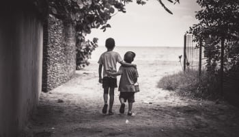 two children holding hands walking on a path