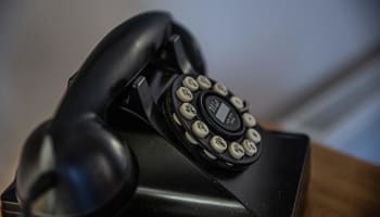 a black rotary telephone with white buttons