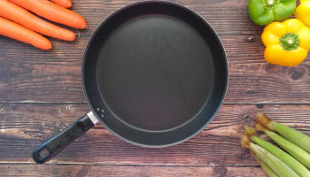 a pan with a handle and a few carrots on a wood surface