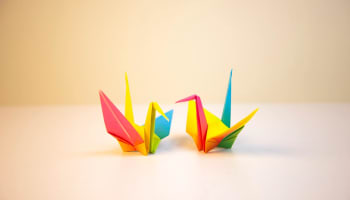 two colorful paper cranes on a white surface