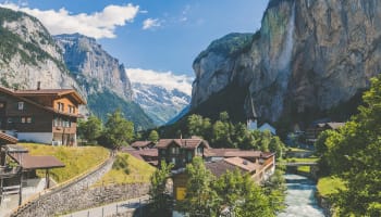 a river running through a valley with buildings and mountains