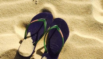 a pair of flip flops in sand