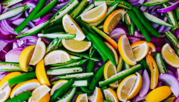 a pile of vegetables with lemons and onions