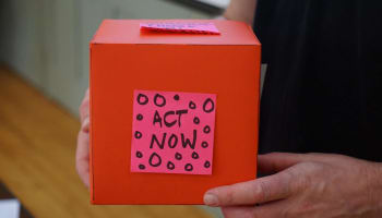 a person holding a box with a sticky note