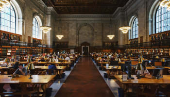 a group of people sitting at tables in a library