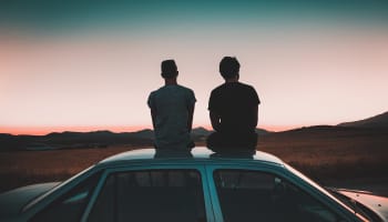 two people sitting on the roof of a car