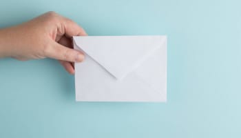 a hand holding a white envelope