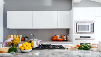 a kitchen with white cabinets and a marble countertop