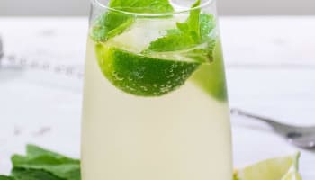 a glass with a drink and a lime and mint leaf