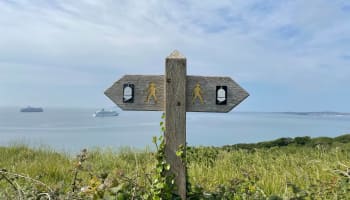 a sign on a pole with a boat in the background