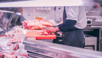 a person cutting meat in a butchery