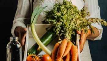a person smiling holding a bunch of greens