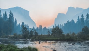 a river with trees and mountains in the background