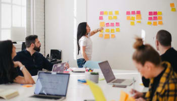 a person pointing at a wall with sticky notes