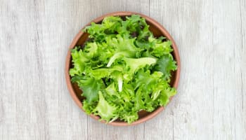 a bowl of lettuce on a wood surface