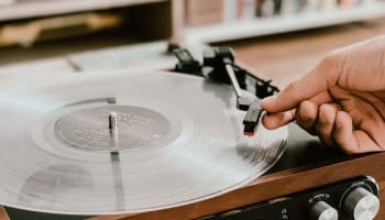 a hand holding a record on a record player