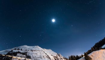 a snowy mountain with a road and a bright star in the sky