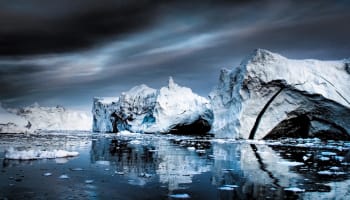 icebergs in the water with a cloudy sky