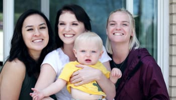 a group of women smiling and holding a baby