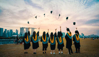 a group of people in graduation gowns throwing hats in the air
