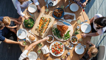 a group of people sitting around a table with plates of food