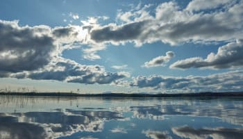 a body of water with clouds and blue sky