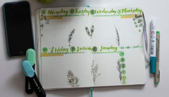 a journal with green leaves and a pen