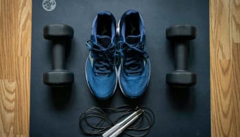 a pair of blue sneakers and dumbbells on a mat