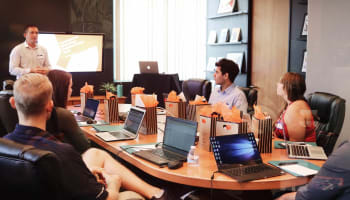 a group sitting at a table with laptops