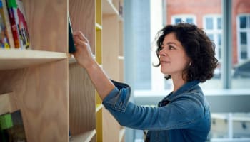 a person looking at a book on a shelf