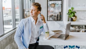 a person sitting at a table with a laptop and phone