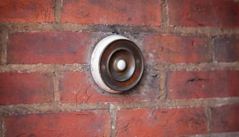 a round metal doorbell with a white light bulb on a brick wall