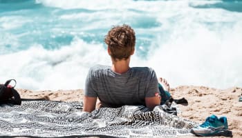 a person lying on the sand looking at the ocean