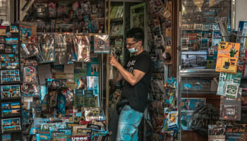 a person wearing a mask and standing in front of a store