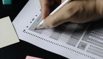 a hand holding a pencil over a test