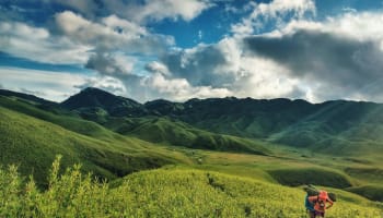 green hills with bushes and clouds