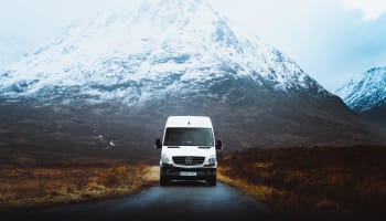 a white van on a road with a mountain in the background