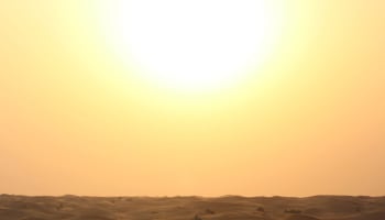 a sandy desert with a bright sun