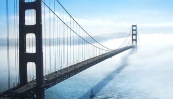 a bridge over water with cars and a sailboat