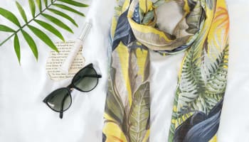 a scarf and sunglasses on a bed