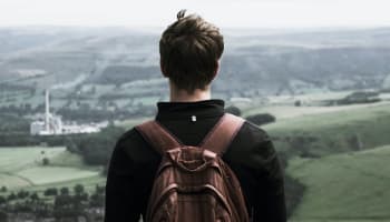 a person with a backpack looking at a valley