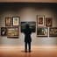 a person standing in front of a wall with paintings